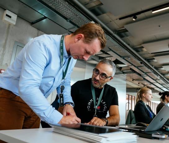 Two men talking whilst one of them takes notes.
