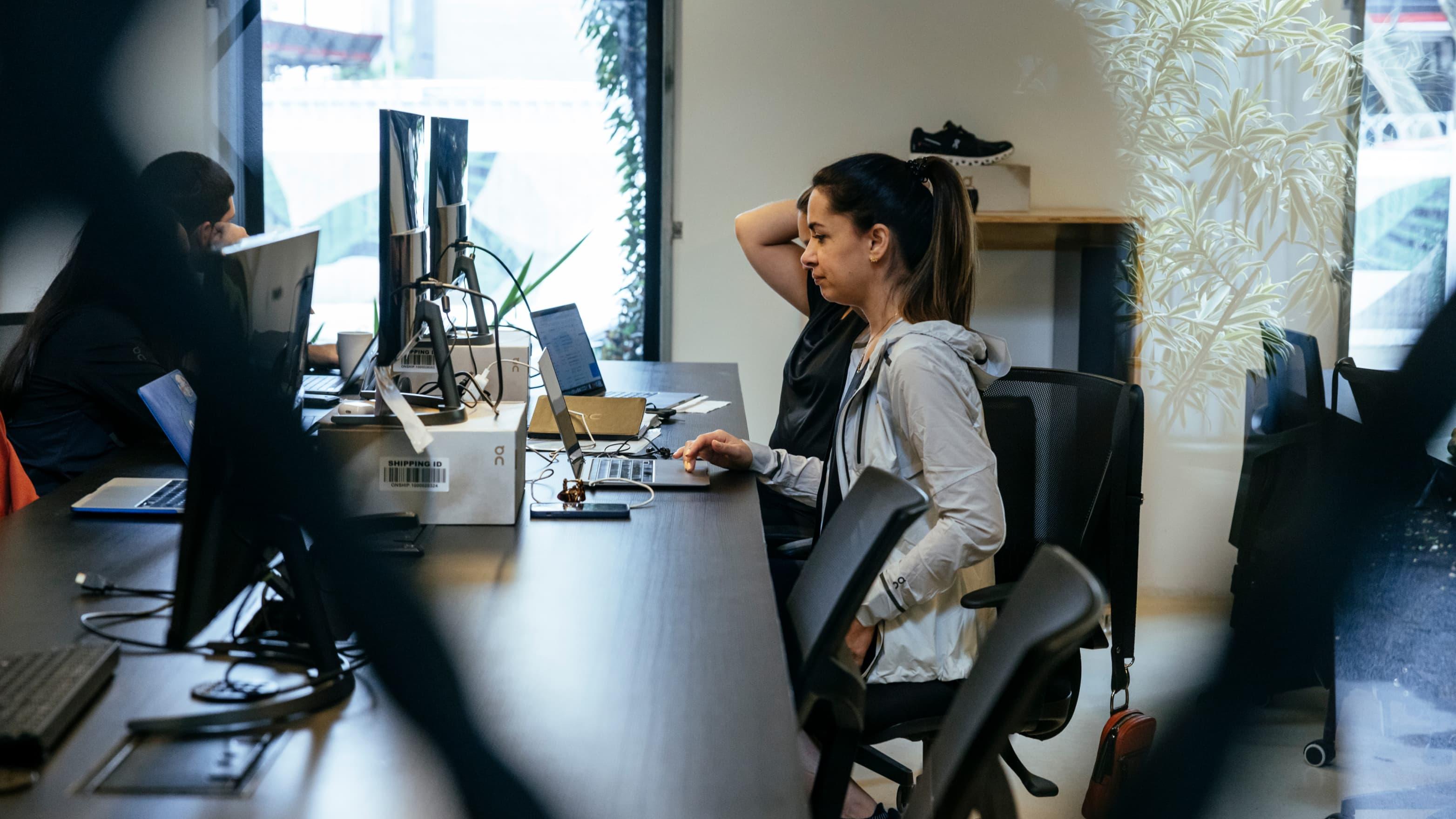 A woman sitting at a desk in an office, talking on a mobile phone