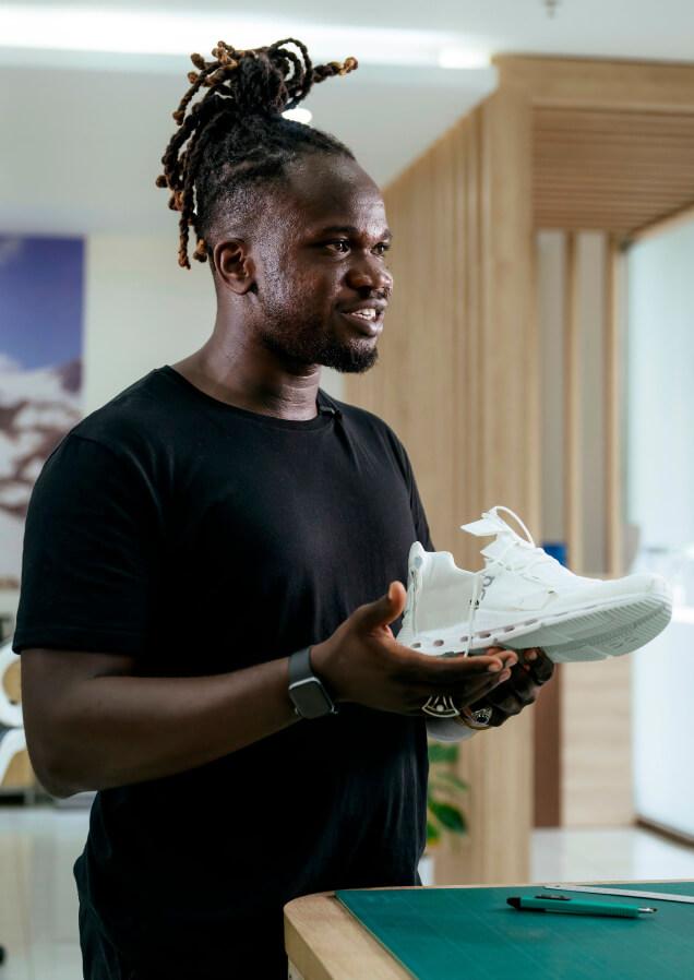 man holding white onrunning trainer in modern office space