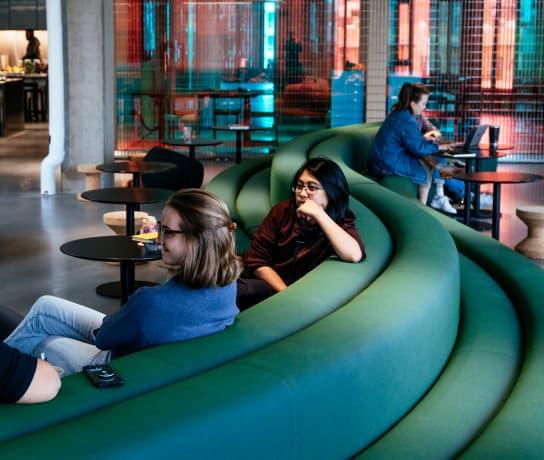 Three people sat on a large curvy sofa in a modern office space.