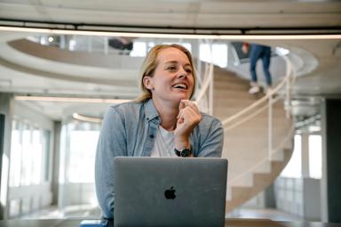 A woman smiling behind a laptop.
