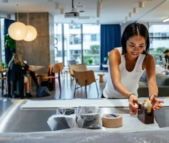 Woman in a white vest top reaching over to get tape