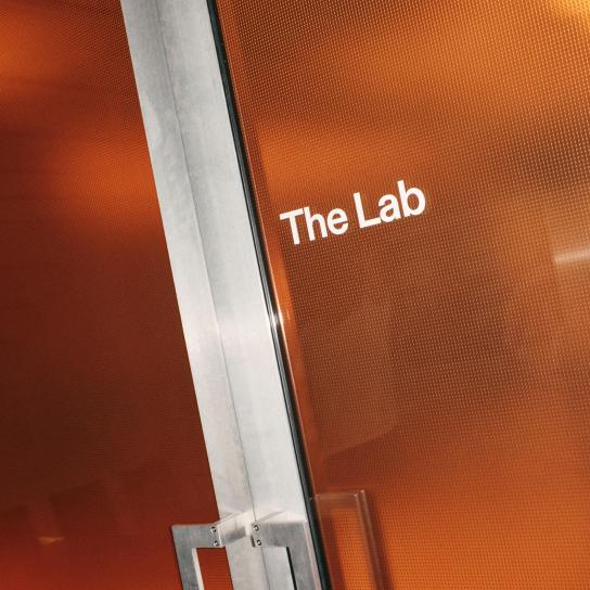 Orange textured translucent door panel labeled "The Lab" in white text with a metal door frame and handle visible on the left.