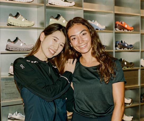 Two females hugging in front a display of running shoes