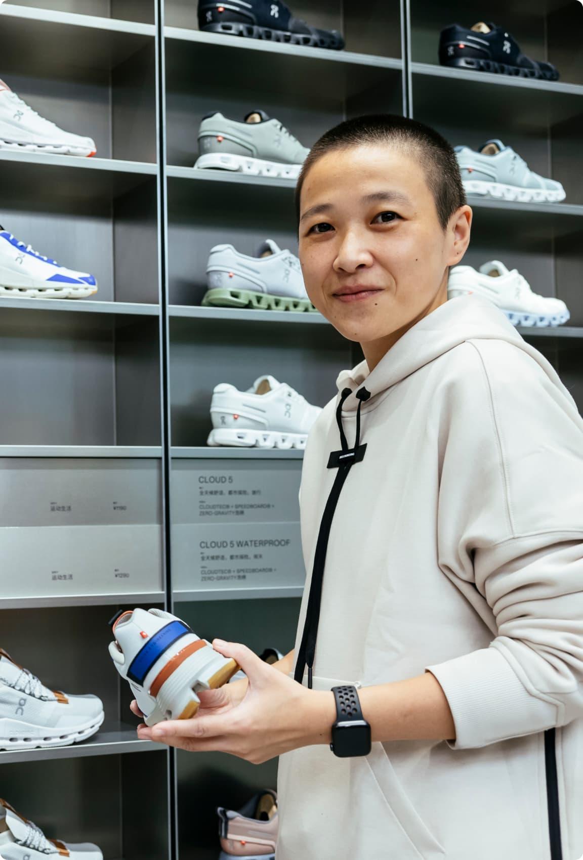 A woman looking towards the camera holding on Onrunning shoe