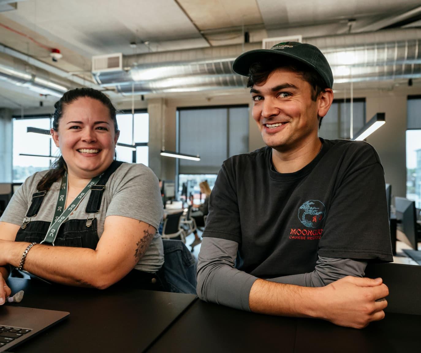 A woman and man in a hat cheekily laughing at the camera