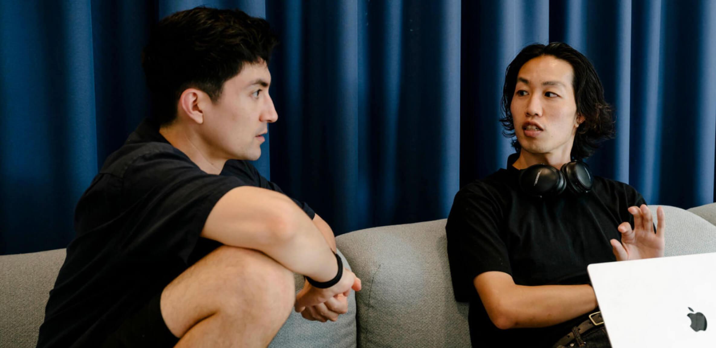 man sitting next to another man working together