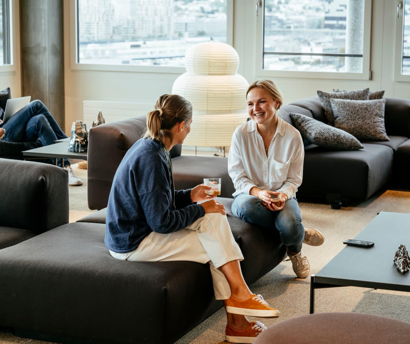 Two woman sat on a sofa having a discussion