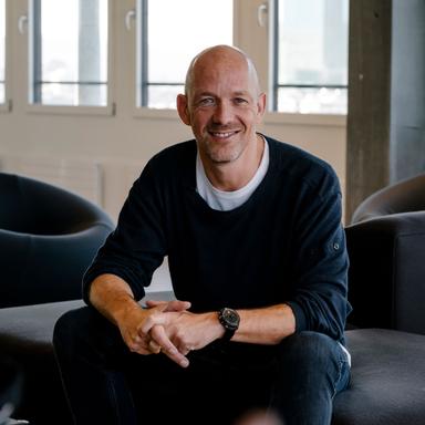 James – Head of Materials Strategy, Zurich is smiling and sitting slightly turned with his arms resting on his knees and hands together