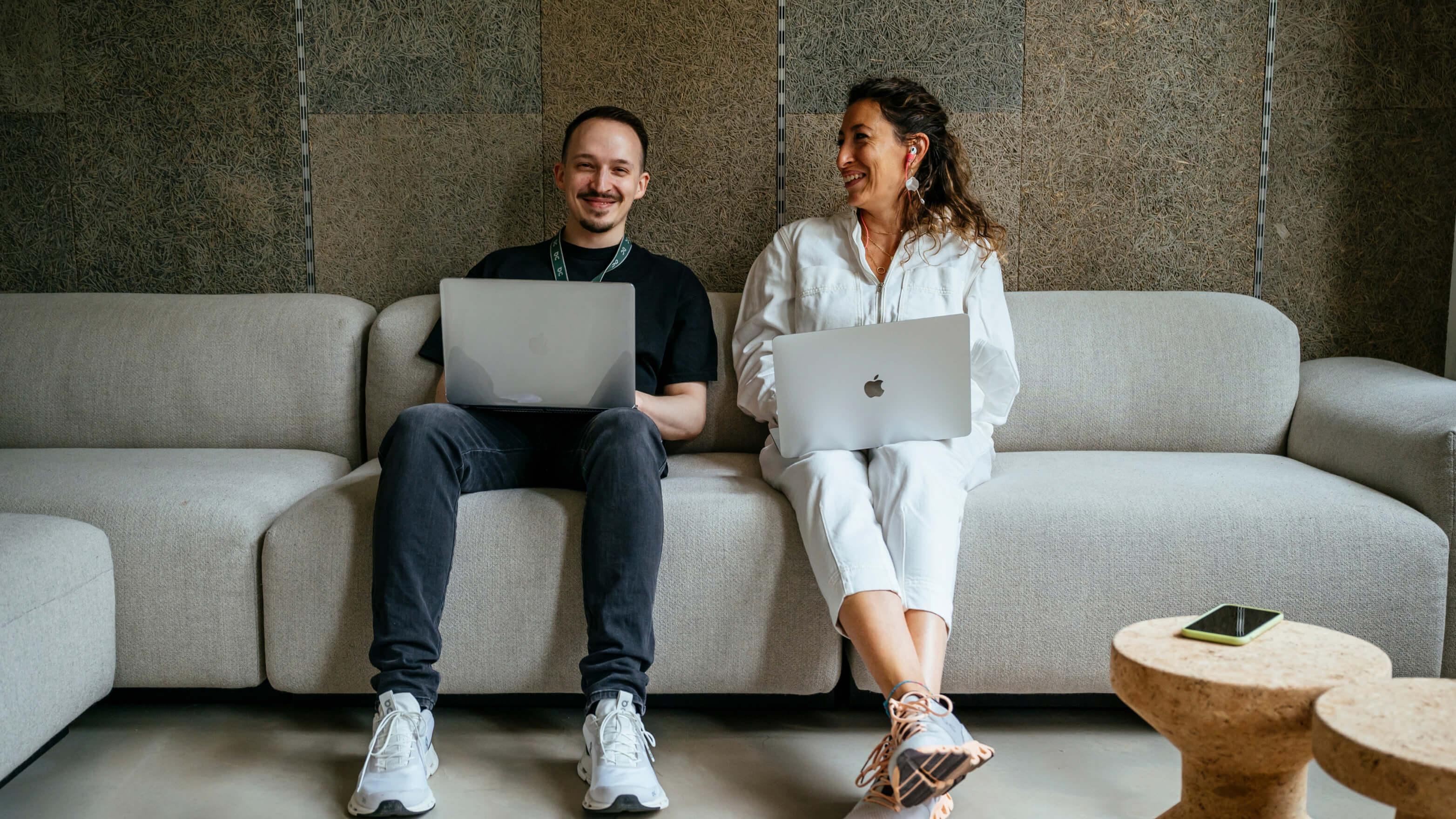 Two happy colleagues smile sitting on the coach