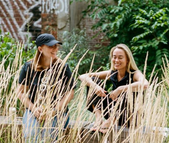 Two women laughing whilst sitting in a garden.