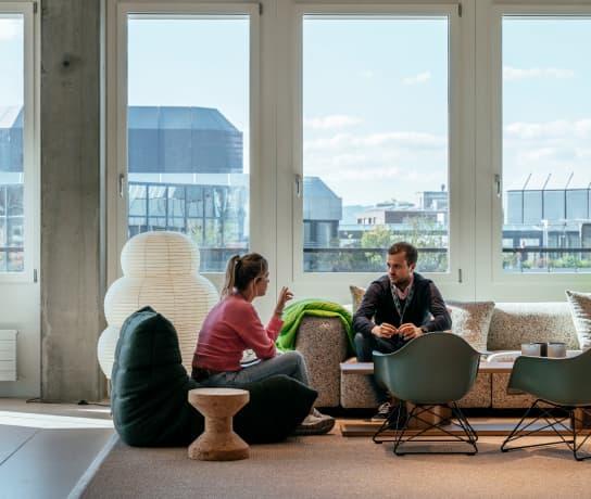 A woman and man sat on sofas talking to each other.