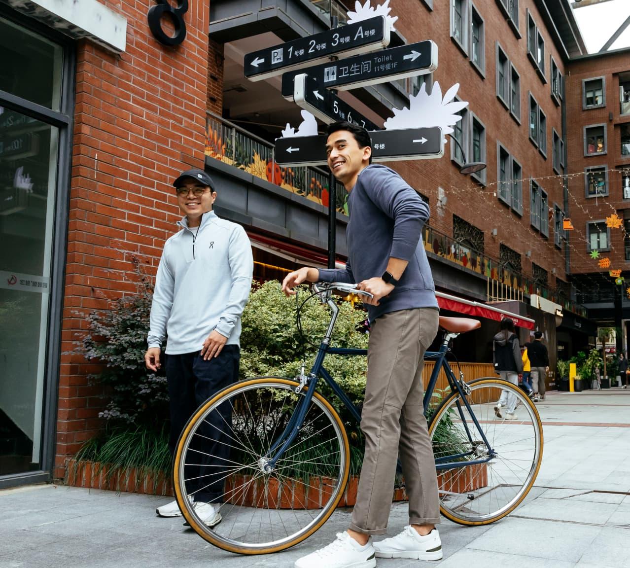 A man on a bike laughing with another man in sports gear