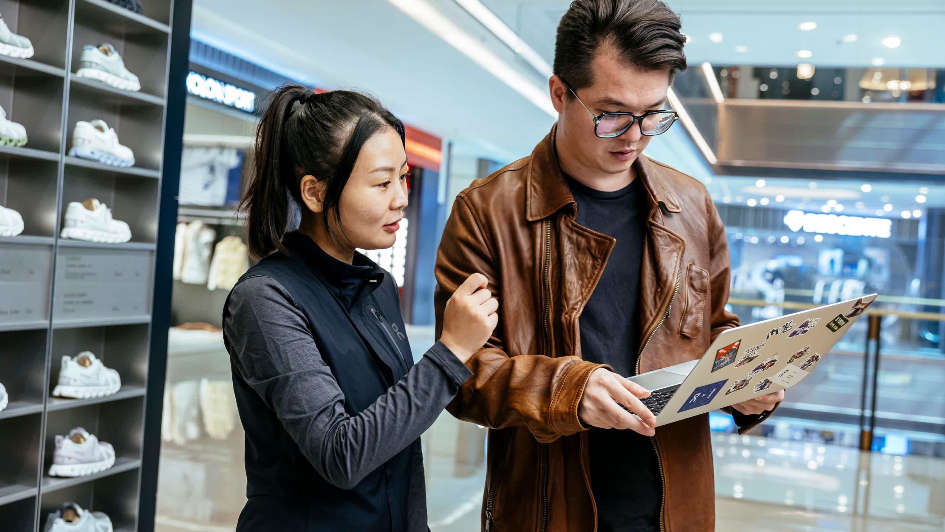 Man and woman look on laptop in the shoes store