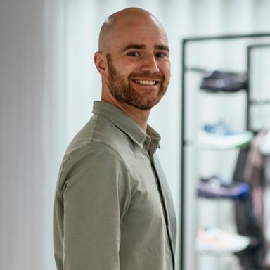A man with his hands in his pockets smiling at the camera.