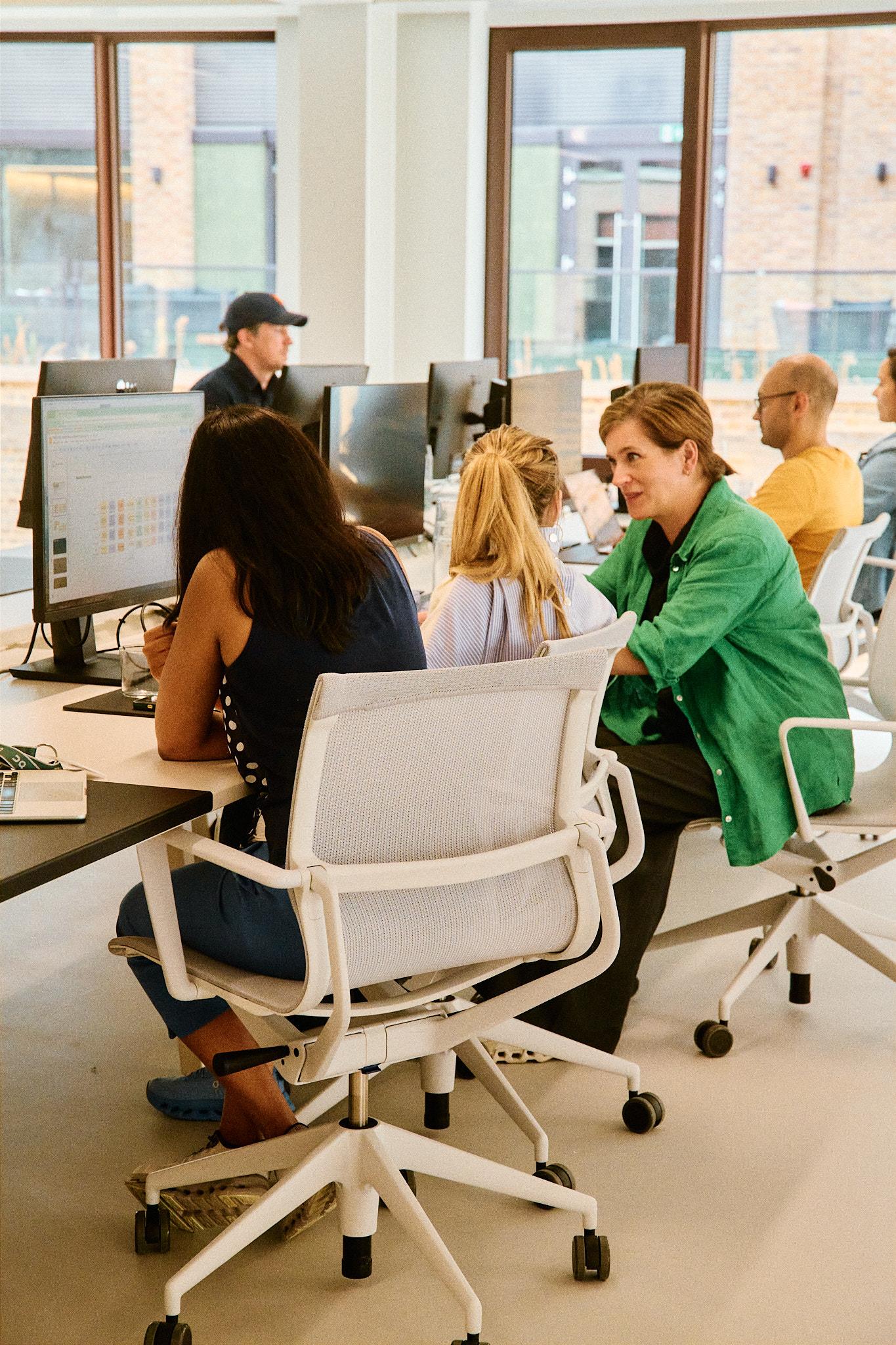 Three people chatting at their desks 