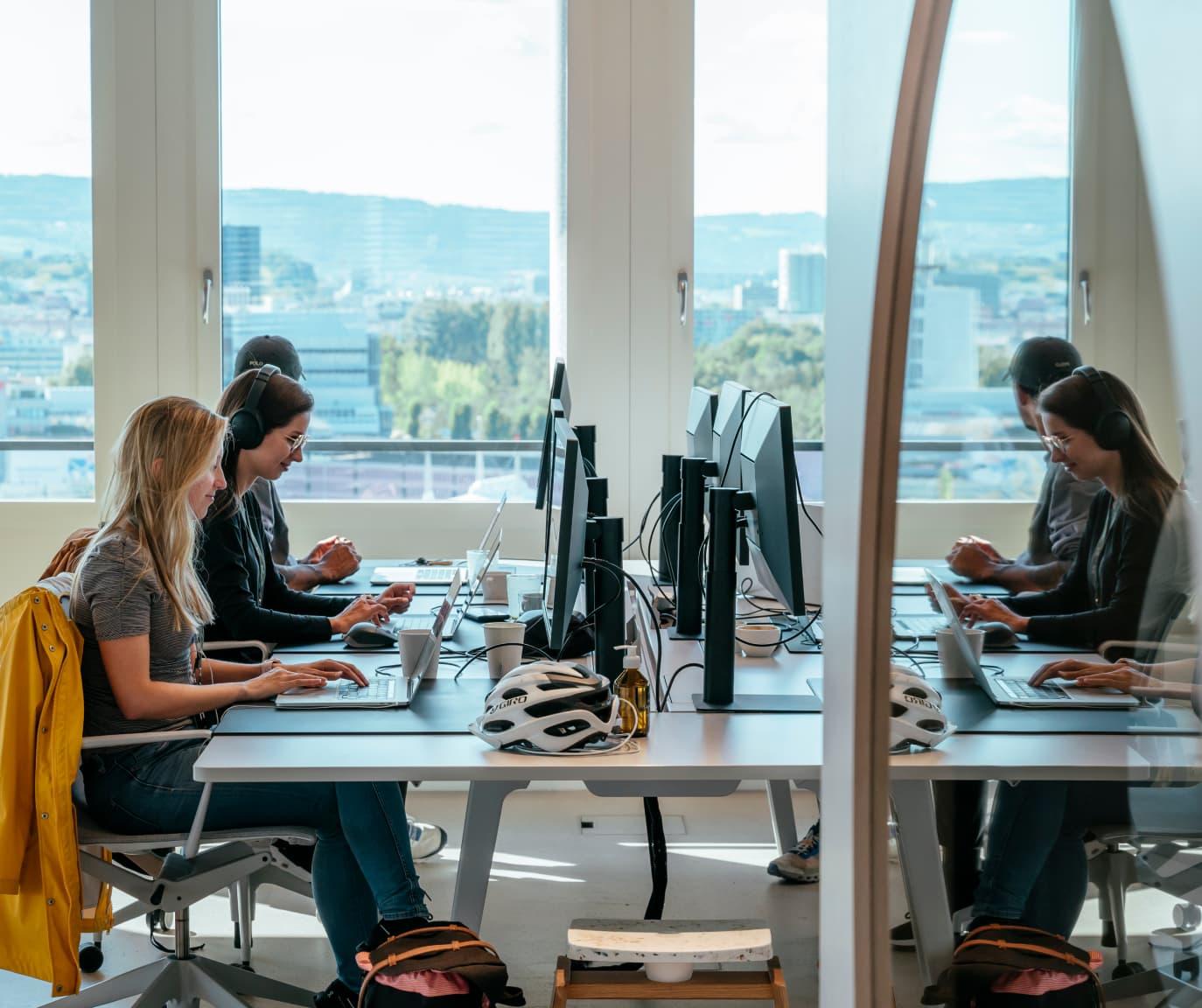 Women sitting at a desk typing on their keyboards.