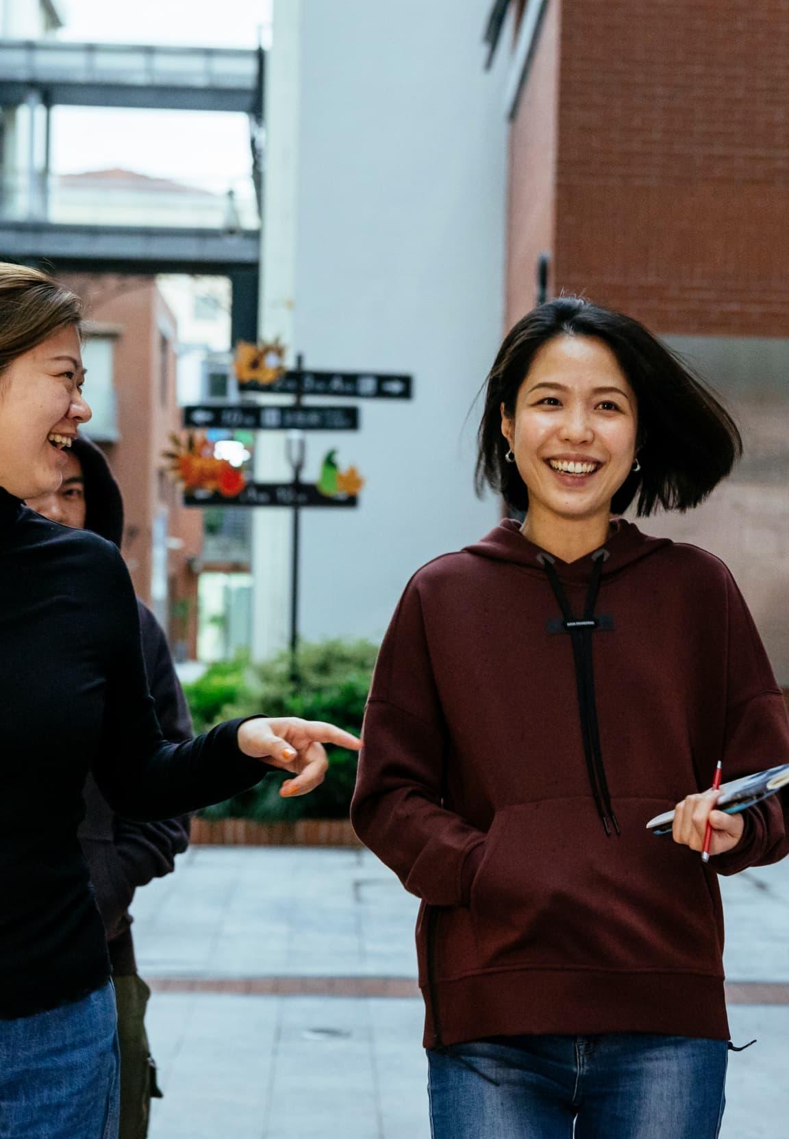 Two women walking down a street whilst smiling in conversation.