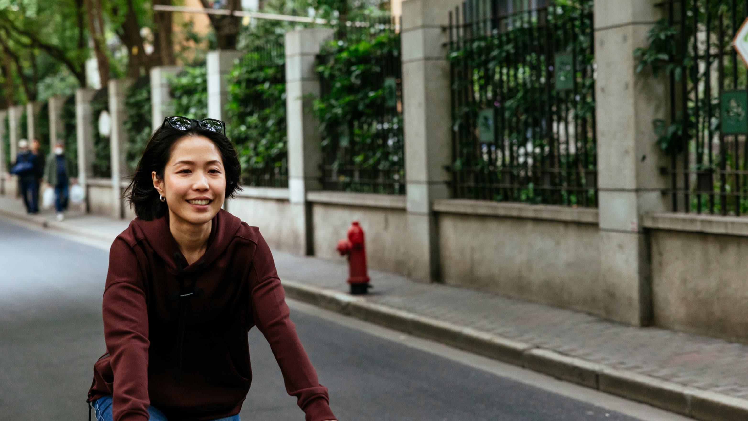 Woman smiles as she rides her bike down a city street
