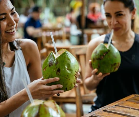 Young women eating coconut water at a street market