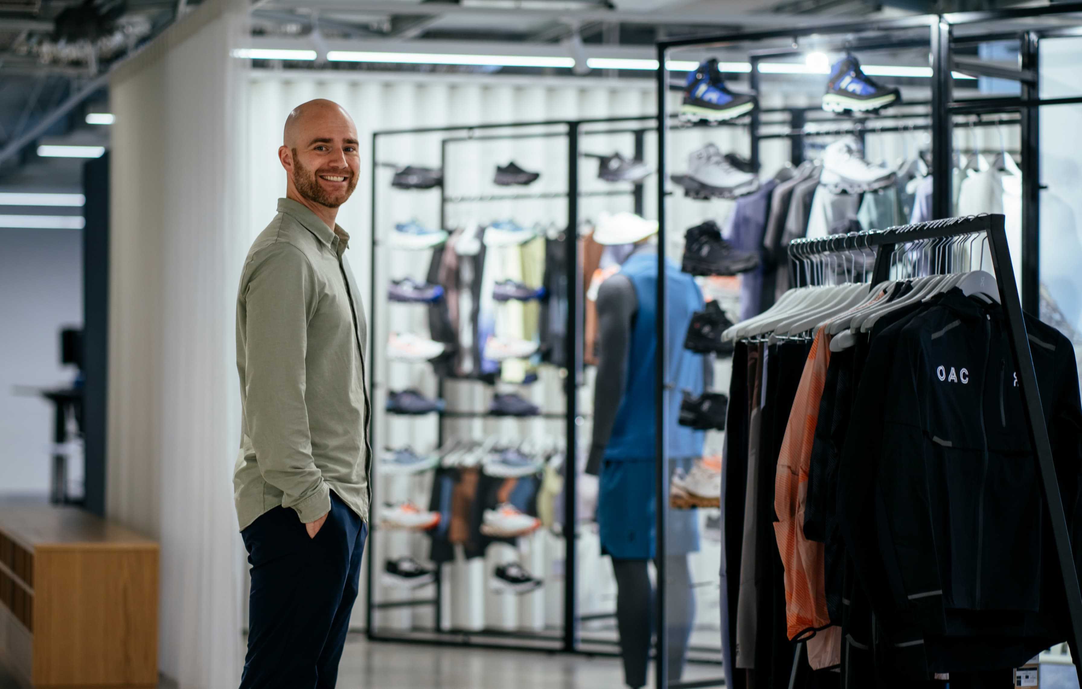 A man smiling whilst standing in an On store.